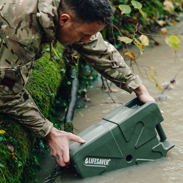 Person in camouflage holding a green 'Lifesaver' Jerrycan in water