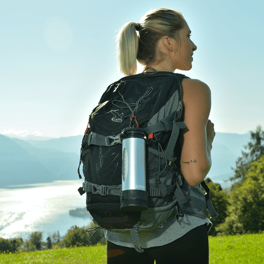 Woman with a backpack and insulated bottle in a mountainous landscape
