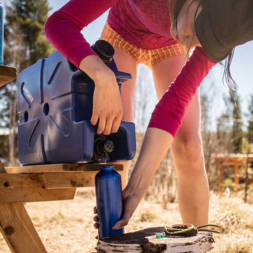 Person using a blue water filter system outdoors